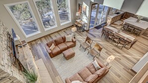 Un vaste espace de vie comprenant un grand canapé en cuir marron, une table à manger en bois et une cuisine dotée de meubles en bois et d’une grande fenêtre.