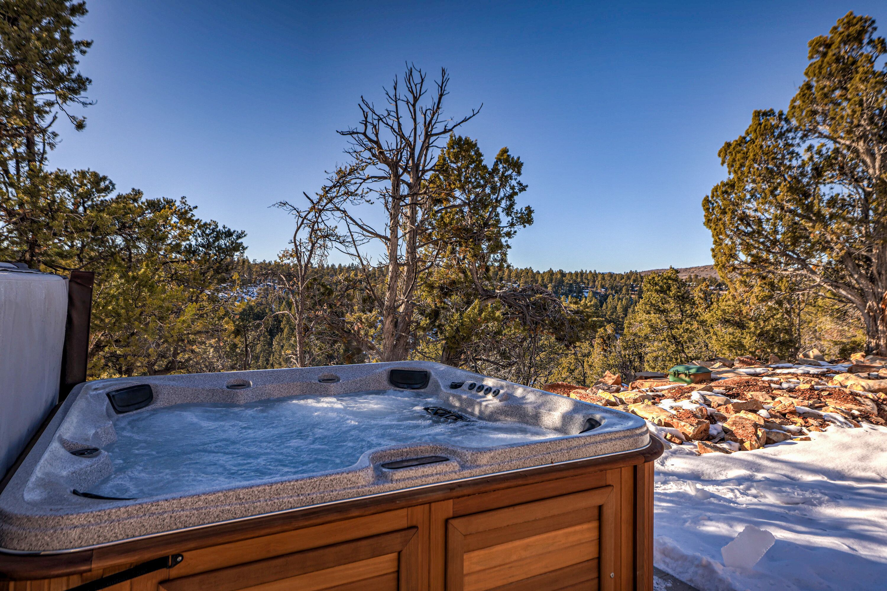 A hot tub in a wooden cabin with a view of a forest and mountains.