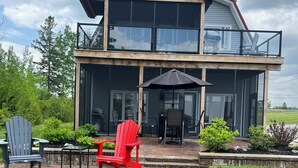A two-story house with a balcony, outdoor seating area, and a well-maintained lawn.