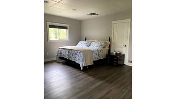 Une chambre à coucher avec un lit, une commode, une fenêtre et une porte.