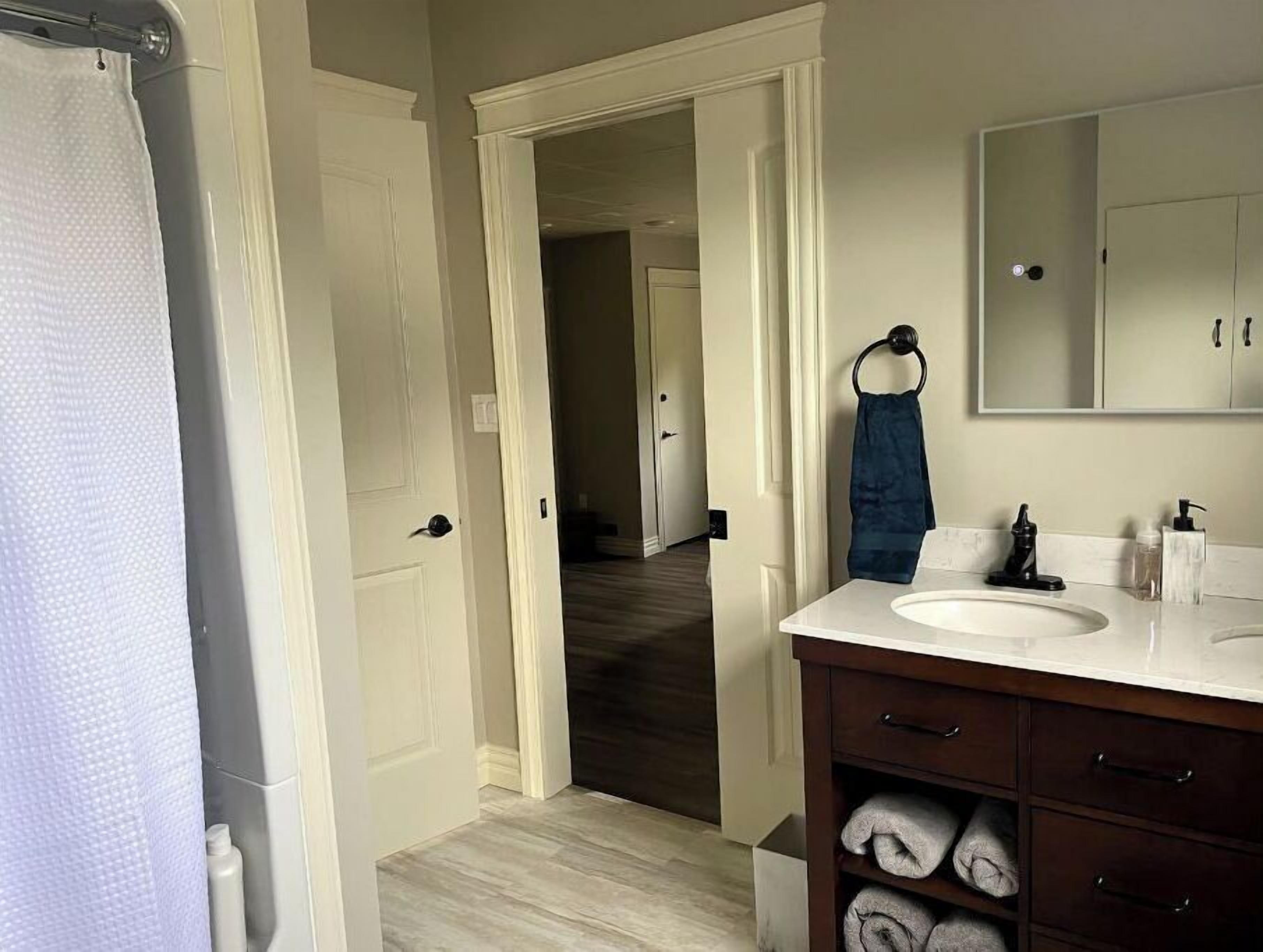 Une salle de bain avec un lavabo blanc, un meuble-lavabo en bois foncé et un miroir au-dessus.