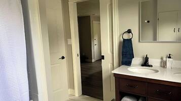 Une salle de bain avec un lavabo blanc, un meuble-lavabo en bois foncé et un miroir au-dessus.