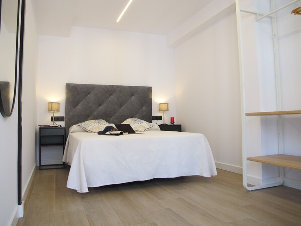 Un dormitorio ordenado con una cama grande, dos mesitas de noche y un armario.