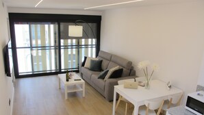 A modern living room with a sofa, a coffee table, a dining table, and a kitchen area with a microwave. - Spectacular penthouse with terrace, 2 bedrooms (Alicante (Alacant))