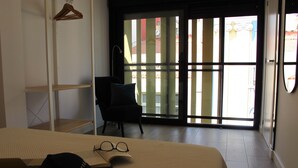 A bedroom with a bed, a chair, a bookshelf, and a window with blinds. - Spectacular penthouse with terrace, 2 bedrooms (Alicante (Alacant))