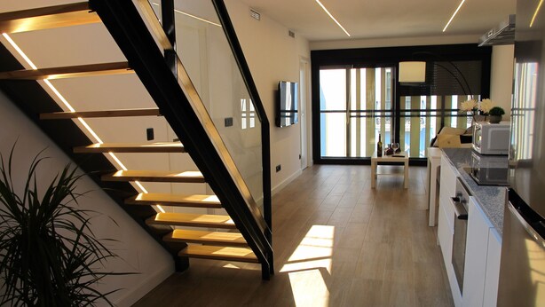 A modern kitchen with a wooden staircase, a potted plant, and a view of the outside. - Spectacular penthouse with terrace, 2 bedrooms (Alicante (Alacant))