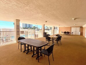 Een overdekt terras met uitzicht op het zwembad, tafels en stoelen.