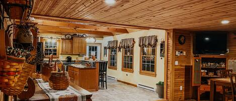 A spacious kitchen with wooden cabinets, a central island, and a dining area with a table and chairs.