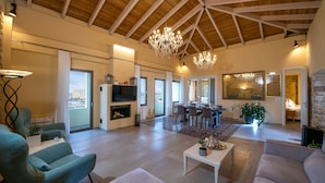 Un salón espacioso con techo alto, chimenea, comedor y un gran ventanal con vistas.