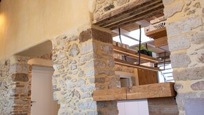 Interior con paredes de piedra, techo de madera, un sofá y un altavoz.