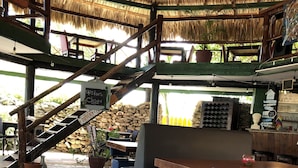Un restaurant doté d’un sol en mosaïque, de meubles en bois et d’un toit de chaume.