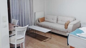 A modern, well-lit living room with a sofa, a coffee table, and a dining area with chairs. - Daylight Rezidans (Istanbul)