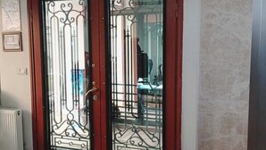 A double door with intricate metalwork, a white ceiling light, and a tiled floor. - Daylight Rezidans (Istanbul)