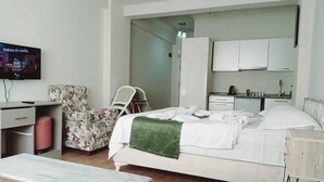 A hotel room with a bed, a desk, a chair, a television, and a kitchenette. - Daylight Rezidans (Istanbul)