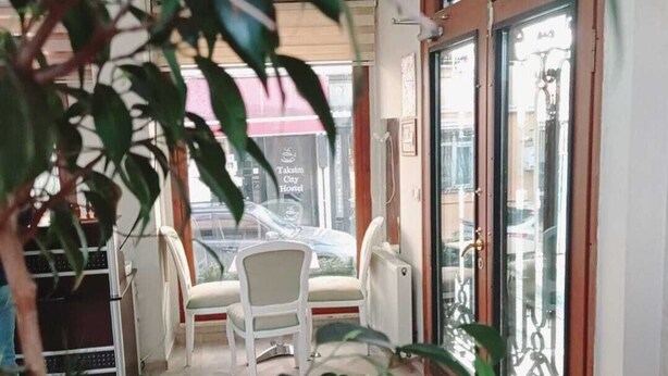 A hotel room with a large window, a dining area with a table and chairs, and indoor plants. - Daylight Rezidans (Istanbul)