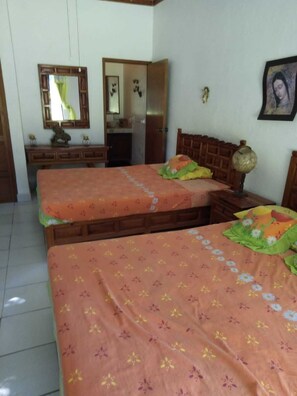 Ein Schlafzimmer mit zwei Betten, einem Schminktisch, einem Spiegel und einer Tür zu einem Badezimmer.