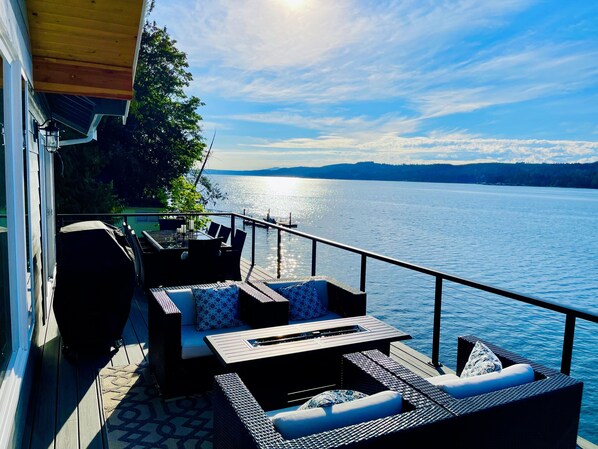 A deck with outdoor furniture overlooking a lake.