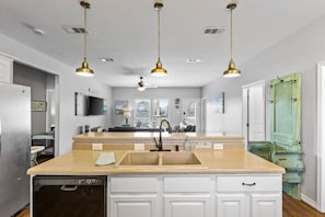 Kitchen features a central island with a double sink and dishwasher, plus pendant lights for ample illumination.