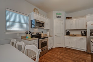 Enjoy cooking in this well-equipped kitchen with a central island, oven, and stainless steel appliances.