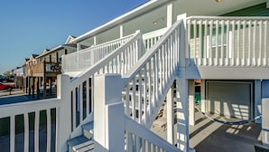A residential building with a white exterior, a covered porch, and a garage.