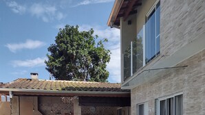 Un jardin avec une piscine, des meubles de patio, un espace barbecue et des plantes en pot.