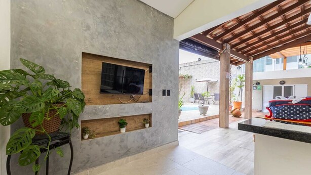 Ein modernes Interieur mit einem an der Wand befestigten Fernseher, einem Blumentopf und einem kleinen Regal mit weiteren Pflanzen.