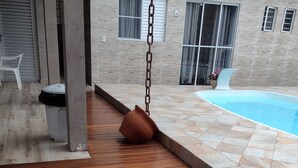 Eine Holzterrasse führt zu einem Poolbereich mit einer Steinmauer und Fenstern im Hintergrund.