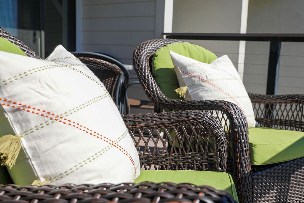 Chaises en osier avec des coussins verts et des oreillers décoratifs.