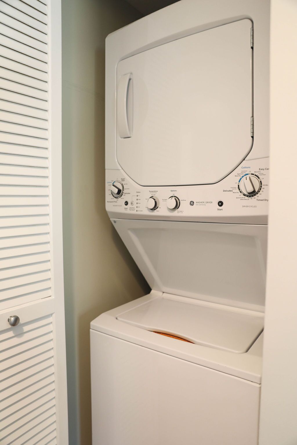 A front view of a white washing machine with control knobs and a door.