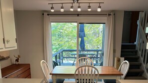 Une cuisine moderne avec un coin repas, des meubles en bois, une cuisinière et une vue sur la verdure environnante.