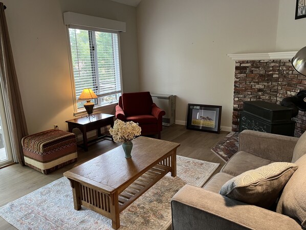 A living room with a fireplace, a red armchair, a wooden coffee table, and a sofa.