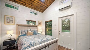 Une chambre à coucher avec un lit, des tables de chevet, une porte et une fenêtre.