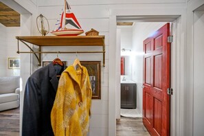 Un pasillo con un perchero, una puerta y una vista parcial de un baño.