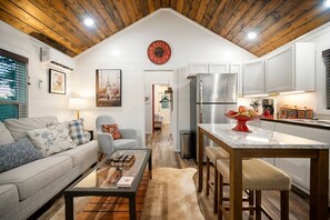 Una sala de estar moderna con sofá, una mesa de centro y un comedor, con una cocina al fondo.