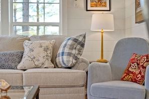 A living room with a sofa, armchair, and a floor lamp.
