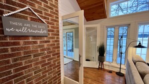 Ein modernes Interieur mit Backsteinwand, Spiegelbild eines Raumes und großem Fenster mit Blick auf eine verschneite Landschaft.