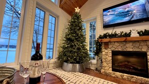 Ein gemütliches Wohnzimmer mit Kamin, Weihnachtstannen und Fernseher.