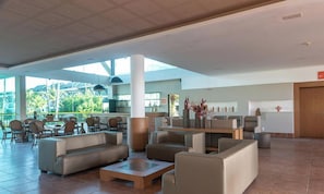 A spacious lobby with modern furniture, a large pillar, and a view of the outdoors.