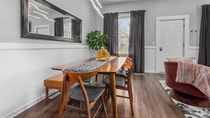 Un coin repas avec une table en bois, des chaises, un miroir et une plante en pot.