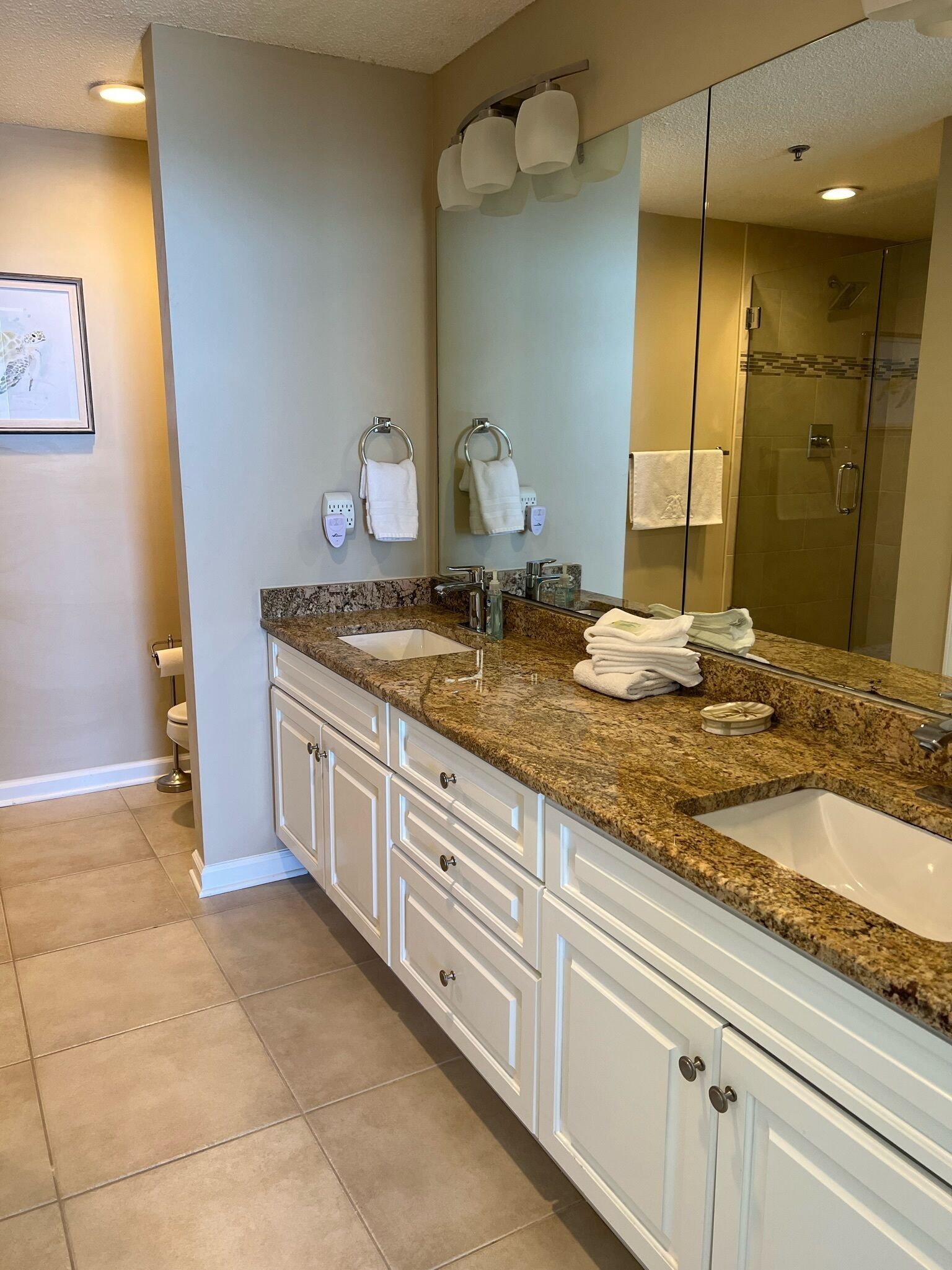 A modern bathroom with two sinks, a large mirror, and a walk-in shower.