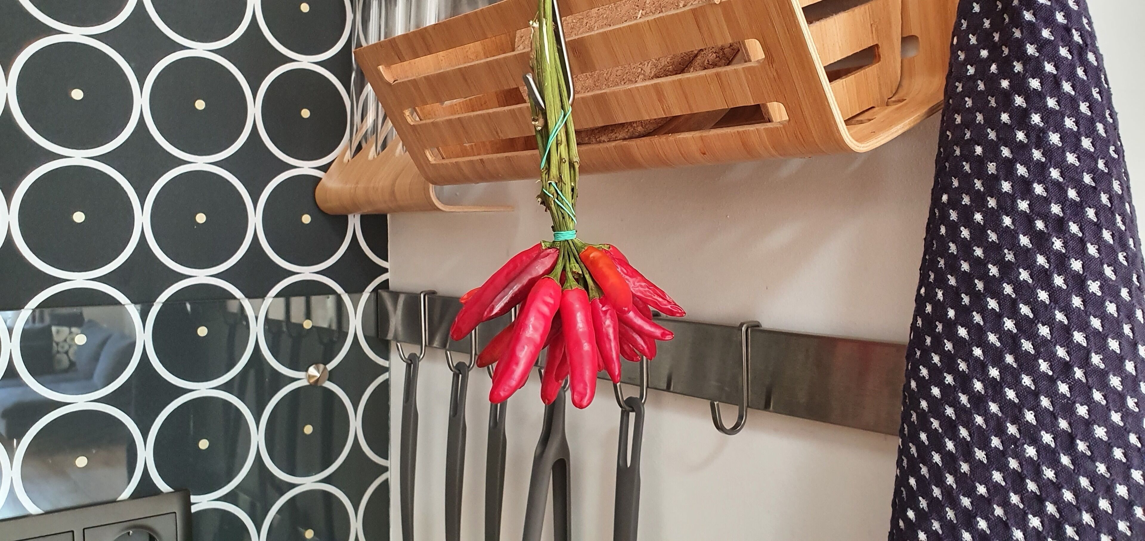 Una cucina con un tagliere di legno, una griglia di peperoncini rossi e una parete decorata.