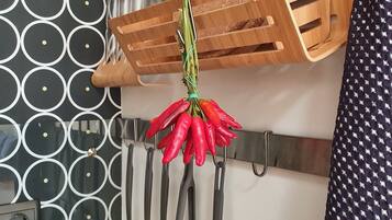 Una cucina con un tagliere di legno, una griglia di peperoncini rossi e una parete decorata.