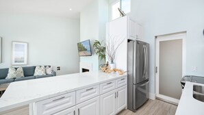 Une cuisine moderne avec des meubles blancs, un réfrigérateur en acier inoxydable et un plan de travail en marbre.