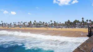 Une plage bordée de palmiers, une promenade en bois et une rive sablonneuse.