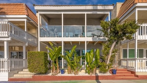 Un immeuble de deux étages doté de balcons, de grandes fenêtres et d’une variété de plantes en pot.
