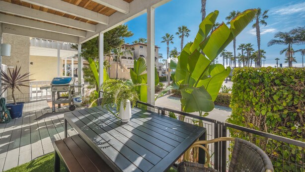 Une terrasse extérieure avec une table et des chaises, entourée de plantes tropicales et de palmiers.