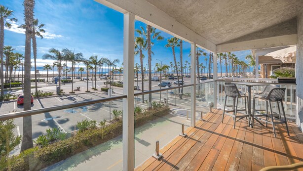 Ein Balkon mit Blick auf Palmen und einen Strand.