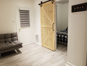 Relax in a spacious living area with a comfortable sofa and cozy bed, featuring a stylish sliding door to a separate bedroom.
