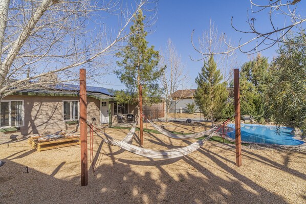 A house with a hammock, a pool, and a fenced yard.