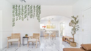 Amplia sala de estar con piso de mármol, muebles de madera y plantas colgantes.